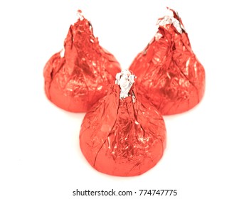 Three piece of milk chocolate in red wrapping macro isolated on white background