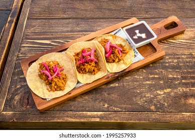 Three Piece Serving Of The Popular Mexican Cochinita Pibil Taco With Purple Onion And Chipotle Sauce In A White Bowl