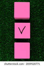 Three Pink Cubes With A Tick On One On Grass. Concept Of Choosing A Better Option, Creating Checklists, Elections And Sports Betting