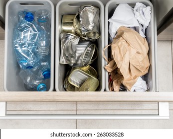 Three Plastic Trash Bins In Kitchen Cabinet With Segregated Household Garbage - PET Bottles, Paper And Metal Cans Shot From Above