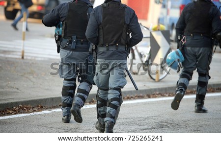three police officers with bulletproof vests riot in uniform patrolling the streets of the city during the anti-terrorism controls