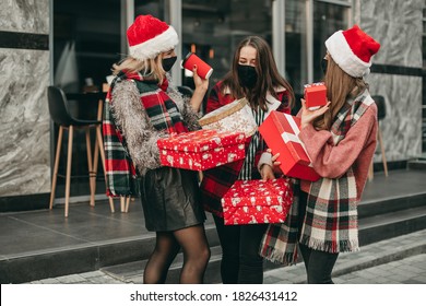 Three portrait of young happy women in red Christmas clothes, medical masks, hats and gifts walking in the city and shopping in quarantine.  