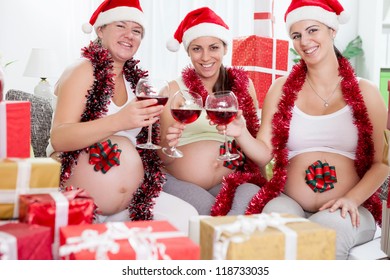 Three pregnant women hat toasting for Christmas, smiling and looking at camera