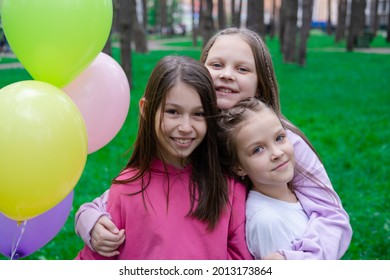 three pretty girls in colorful clothes hugging near hot air balloons. sisterhood, friendship, bff. summertime.