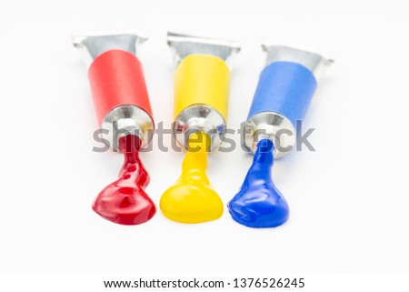 Three of the primary colour flow out of the tube on rough white paper