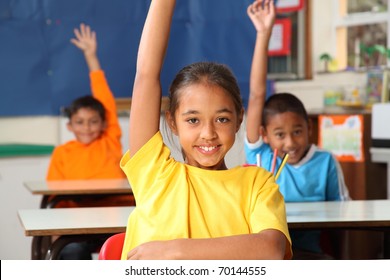 Three Primary School Children Hands Raised In Class