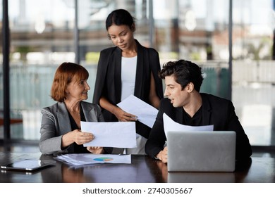 Three professionals analyzing documents in a modern office