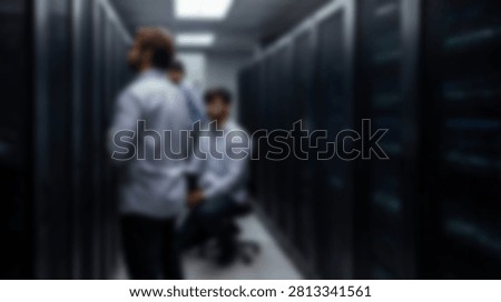 Three IT professionals in a dimly lit data center, surrounded by rows of server racks, discussing technology and infrastructure.