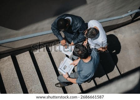Three professionals discussing project documents during an impromptu team meeting on a staircase.