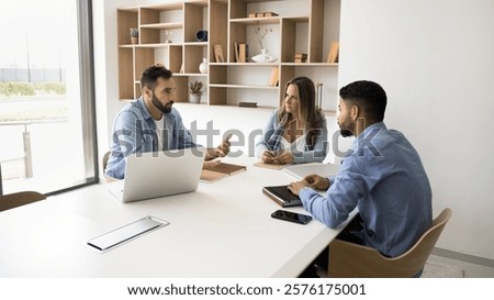 Three professionals sit at conference table engaged in project discussion, gathered together for planning budget allocation and resources, share business strategies, team responsibilities. Workflow