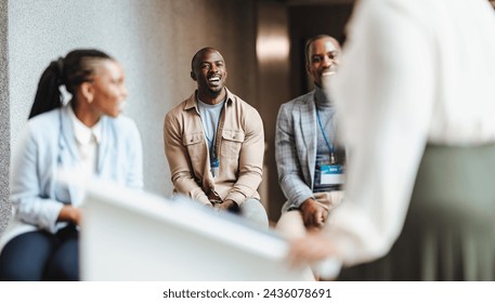 Three professionals smiling and engaging in a casual conversation with speaker. Business people conveying a sense of teamwork, networking, and positive workplace interaction in a corporate setting. - Powered by Shutterstock