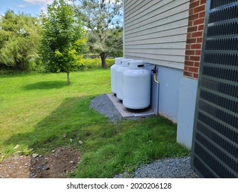 Three propane tanks on the outside of a home.