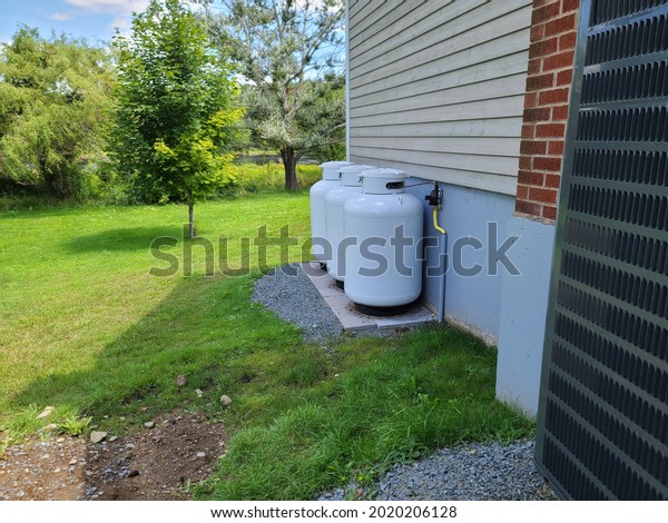 Three propane\
tanks on the outside of a\
home.