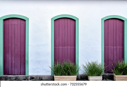 Three Purple Doors Down Street In The Small Village. Wooden Door In The Colonial Style