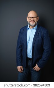 Three Quarter Length Portrait Of Confident Mature Man With Facial Hair And Eyeglasses Wearing Business Casual Clothing And Standing In Studio With Dark Gray Background And Copy Space