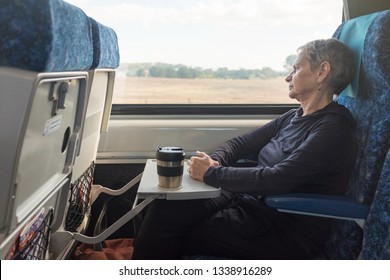 Three Quarter Length View Of Senior Woman With Grey Hair In Train Seat With Reusable Coffee Mug (selective Focus)