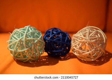 three rattan blue balls on top of orange canvass with orange background