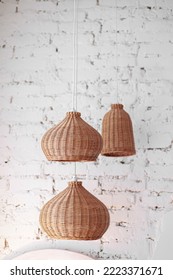 three rattan chandeliers different forms on white brick wall background. Straw lampshade in cozy living room. Eco-friendly interior design using natural materials. Scandinavian interior. copy space.