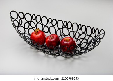 Three Red Apples Inside A Long Fruit Bowl With Cut Out Circles Pattern, Isolated On White