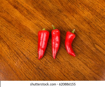 Three Red Jalapeno Peppers On Wood Table