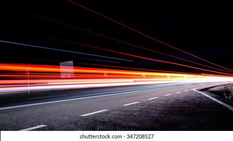 Three red lines / red light trails at night on the road