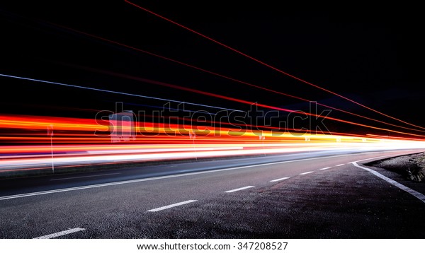 Three\
red lines / red light trails at night on the\
road
