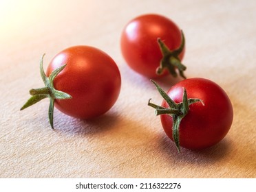 three red ripe small cherry tomatoes in the sun