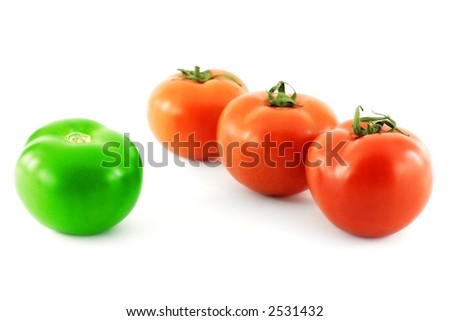 Three red tomatoes standing against a green one
