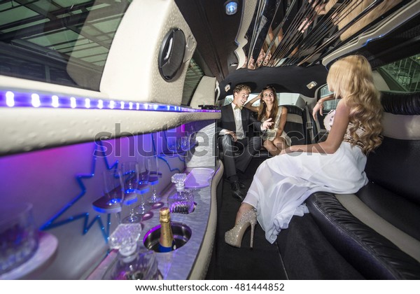 Three rich\
and famous people, celebrities, sitting in a luxurious limousine,\
chatting away, having a good\
time.