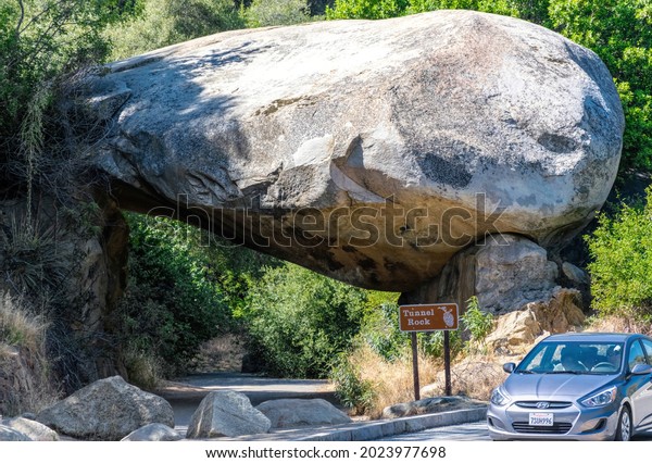 Three rivers, California, USA - June 14 2019:\
giant natural stone arch Tunnel rock and a touring car near the\
entrance to Sequoia National Park in California USA. Summer travel\
natural parkland