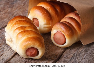 Three Roll With Sausage Close Up In A Paper Bag On A Wooden Background Horizontal 