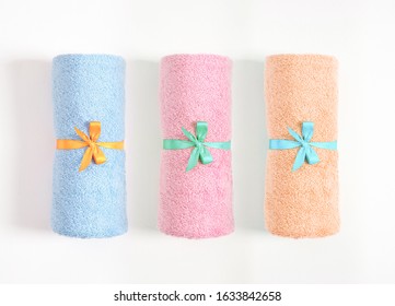 Three rolled towels tied by blue and yellow ribbon isolated, blue, pink and orange terry towels against a white background. Top view. - Powered by Shutterstock