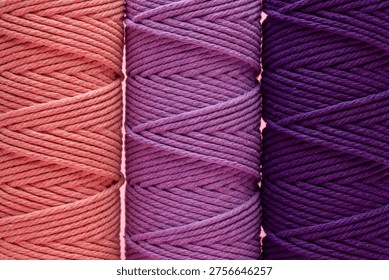 Three rolls of braided macrame cord in various shades of purple and coral pink.