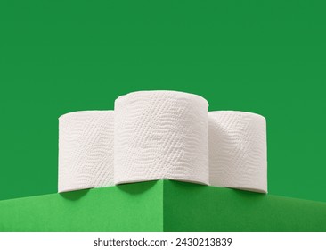 Three rolls of soft white toilet paper on a green background. Housework and cleaning. - Powered by Shutterstock