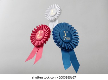 Three rosettes fly over gray background as prizes to winners and champions for quality and victory.