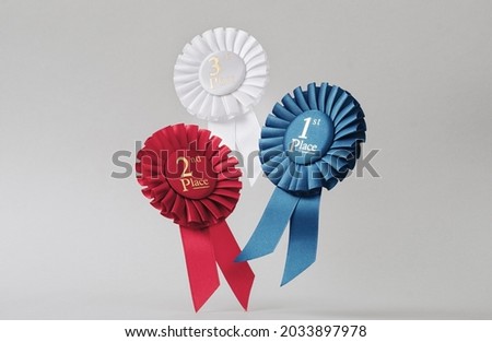 Three rosettes fly over gray background as awards to winners and champions for success and victory.