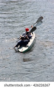 Three Rowers In Kayak Rowing On A River