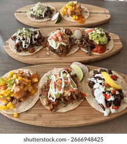Three rows of assorted tacos arranged on wooden boards