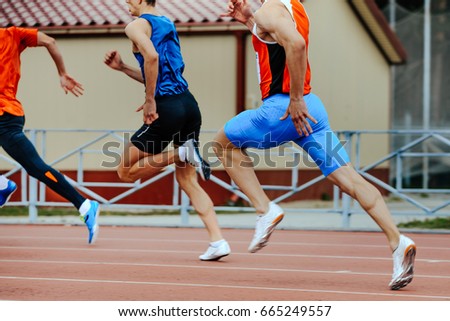 three runners sprinters men run in stadium on competition