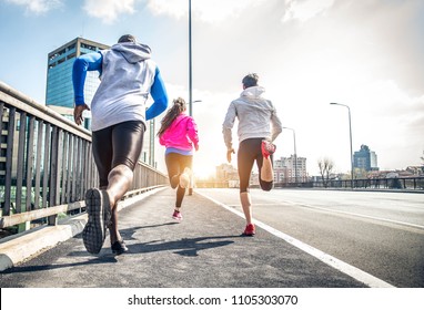 Three runners sprinting outdoors - Sportive people training in a urban area - healthy lifestyle and sport concepts