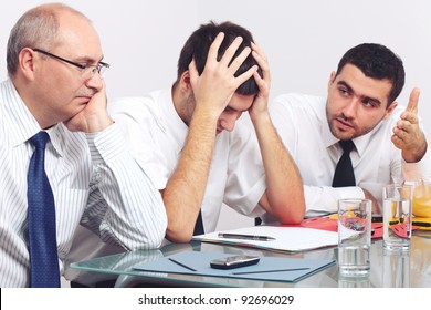 Three Sad And Depressed Businessman Sitting At Table During Meeting