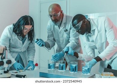 Three Scientists Working with Beakers in the Lab - A diverse team of researchers engages with beakers on a hot plate, captivated by the effervescing blue solution.