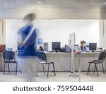 Three seats in front of a Bank, customs, office, hospital, etc. registration desk with blurred figures of a clerk and a customer.