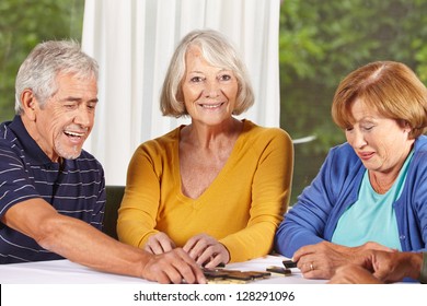Three senior citizens playing a domino game in a nursing home