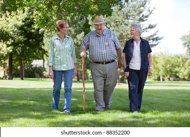 Three Senior Friends Walking In Park During Summer