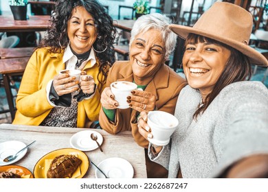 Three senior women enjoying breakfast drinking coffee at bar cafeteria - Life style concept with mature female taking selfie picture with smart mobile phone device - Powered by Shutterstock