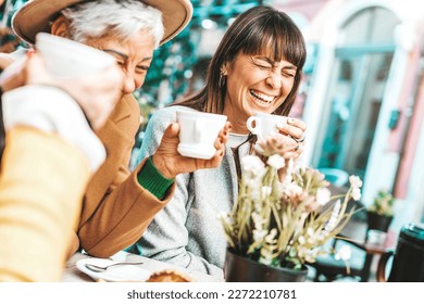 Three senior women enjoying breakfast drinking coffee at bar cafeteria - Life style concept with mature female having fun hanging out on city street  - Powered by Shutterstock