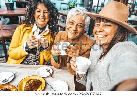 Three senior women enjoying breakfast drinking coffee at bar cafeteria - Life style concept with mature female taking selfie picture with smart mobile phone device