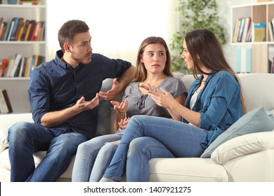 Three Serious Friends Talking Sitting On A Couch In The Living Room At Home