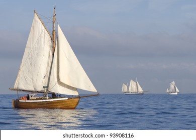 Three Ships With White Sails In The Calm Sea